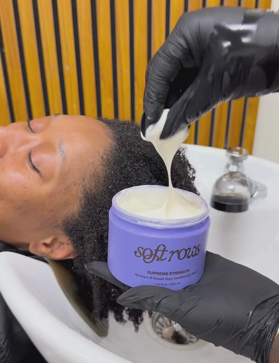 Stylist applying Soft Rows Supreme Strength Deep Conditioning Mask to freshly washed textured hair in salon